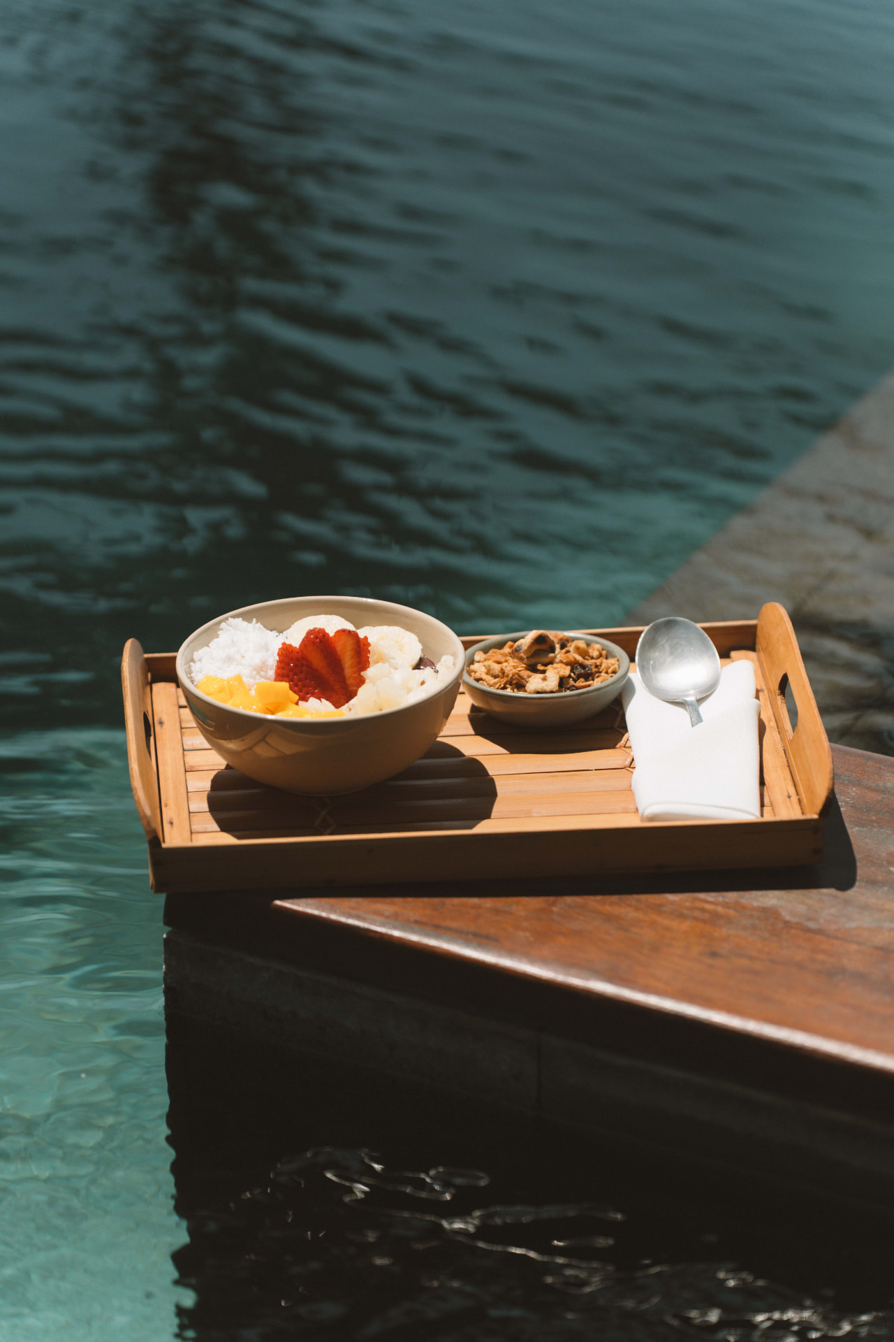 Tigela de frutas com granola servida na beira da piscina